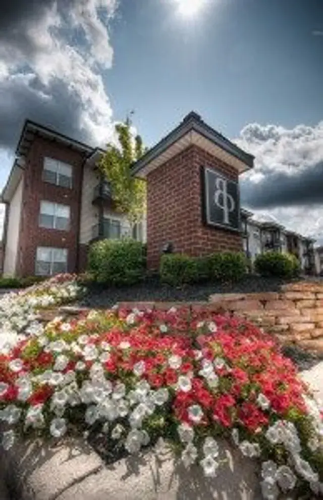 Brick monument sign at an apartment community surrounded by petunias and a stone wall